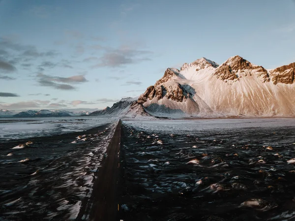 Bir dağ bir kar üzerinden doğru giden bir yol Stokksnes, İzlanda manzara kaplı. Fotoğraf bir dron kullanarak alınır.