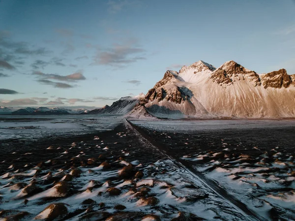 Bir dağ bir kar üzerinden doğru giden bir yol Stokksnes, İzlanda manzara kaplı. Fotoğraf bir dron kullanarak alınır.