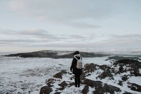 在冰岛 Stokksnes 一个人在雪地上漫步 覆盖着悬崖边的海面上 — 图库照片