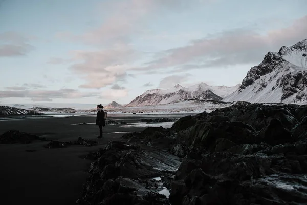 一个人站在黑色沙滩上 Stokksnes 冰岛的积雪景观前 — 图库照片