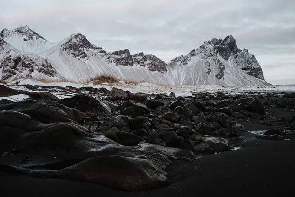 Felsen Einem Schwarzen Sandstrand Vor Einer Verschneiten Landschaft Stokksnes Island — Stockfoto