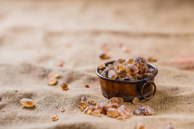 Kahverengi, yapılandırılmış arka planda duran küçük bir tencerede kaya şekeri serpiştirilmiş.