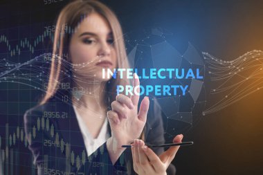 İş, teknoloji, internet ve şebeke kavramı. Genç bir girişimci geleceğin sanal ekranı üzerinde çalışıyor ve yazıyı görüyor: fikri mülkiyet