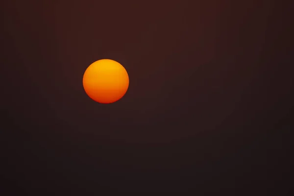 黄色和红色完美圆形发光的太阳对一个黑暗的后背 — 图库照片
