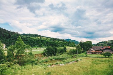 Karpat Dağları'nda geleneksel eski ahşap ev. Toprak yolun dağ gorge eski ahşap evleri ile yalnız uzak köy yol açmaktadır. Geleneksel tarzı Romanya, Bucovina ahşap vintage evi.