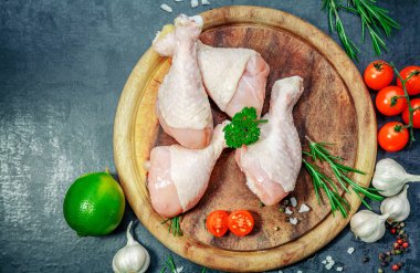 Çiğ çiğ tavuk budu, sopaları ahşap tahta, et yemek pişirmek için malzemelerle üzerinde