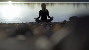 Yoga kadın kalan nehir banka ve meditatting.