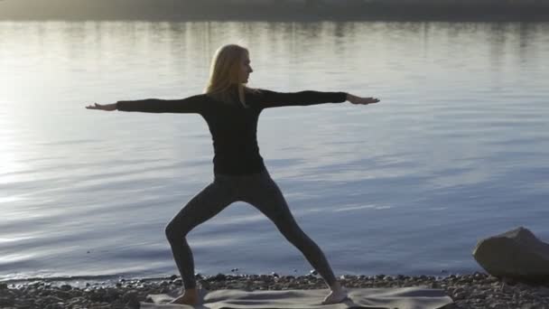 Femme de yoga restant sur la rive de la rivière et méditant . — Video