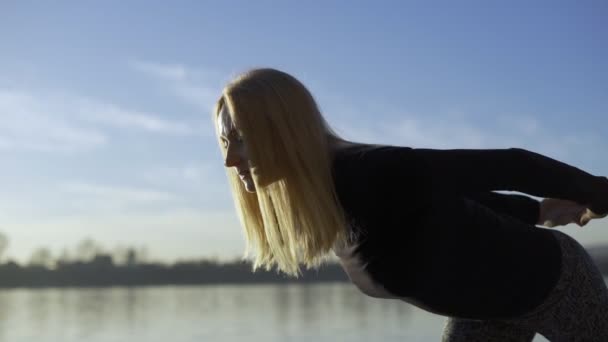 Yoga vrouw verblijft op de rivier bank en meditatting. — Stockvideo