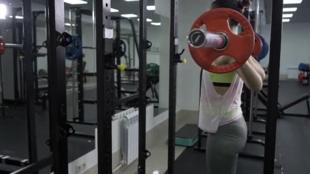 Chica joven haciendo sentadilla de servicio pesado en el gimnasio con barra — Vídeo de stock