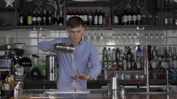 Barman está sirviendo un cóctel alcohólico a través de un colador — Vídeo de stock