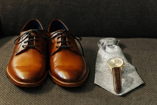 closeup of groom\'s shoes, watches and tie. getting ready? dark background