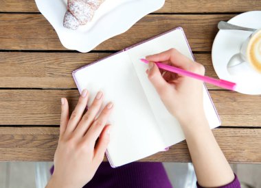 Kadının elleri defter kafede, yazma. Blogger'ın çalışma ve dinlenme üstten görünüm, düz yatıyordu