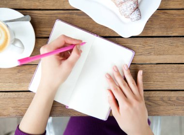 Kadının elleri defter kafede, yazma. Blogger'ın çalışma ve dinlenme üstten görünüm, düz yatıyordu