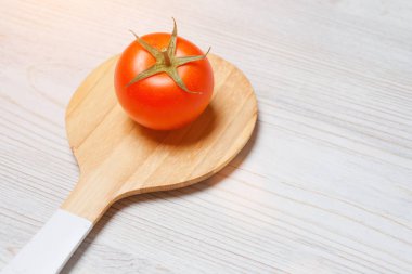 Beyaz ahşap arka planda, tahta kaşık taze kırmızı domatese yakın çekim