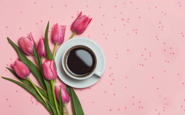 Bir fincan kahve, Pembe lale pembe bir arka plan üzerinde. Çok güzel selamlar. üstten görünüm, düz yatıyordu.