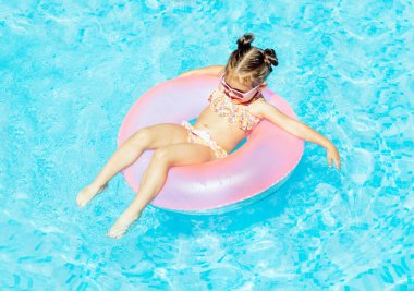 Yüzme Havuzu Float güneş gözlüklü ve having fun halka, şirin ve komik küçük kız yüzme havuzunda. Smmer yaşam tarzı kavramı