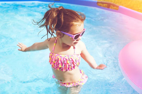 Yüzme Havuzu Float güneş gözlüklü ve having fun halka, şirin ve komik küçük kız yüzme havuzunda. Smmer yaşam tarzı kavramı
