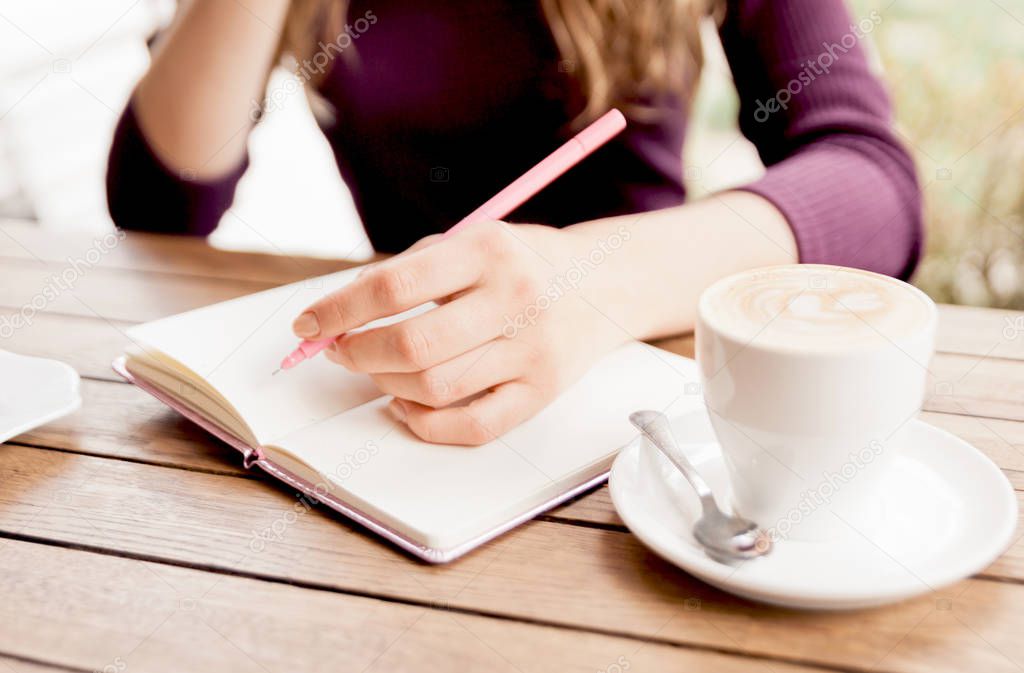 Woman's Hands writting at notebook in cafe. Blogger's life