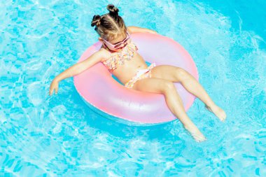 Yüzme Havuzu Float güneş gözlüklü ve having fun halka, şirin ve komik küçük kız yüzme havuzunda. Smmer yaşam tarzı kavramı
