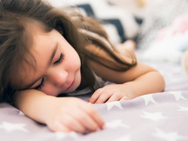 Sevimli mutlu küçük kız uyku ve içinde rüya ve onun oyuncak sarılma yatak. Uyuyan çocuğunun fotoğrafı kapatın.