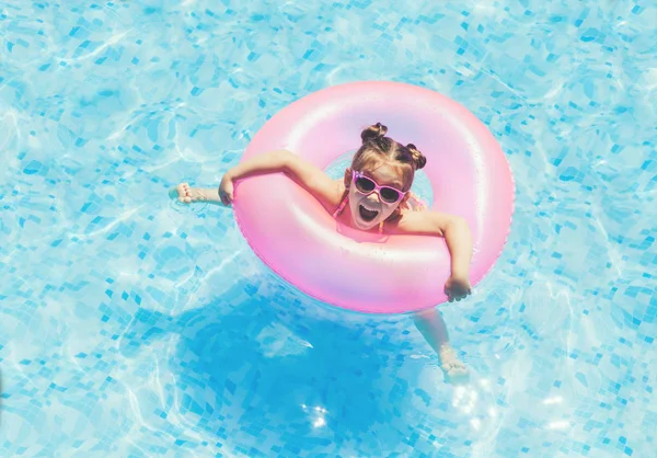 Yüzme Havuzu Float güneş gözlüklü ve having fun halka, şirin ve komik küçük kız yüzme havuzunda. Smmer yaşam tarzı kavramı