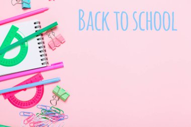 Pembe renkli arka plan çeşitli okul aksesuarları ile bir gökkuşağı şeklinde koyulur. Satır, ham. Düz yatıyordu üstten görünüm. Düzenleme çalışması. Merkezi okula geri kelimeler ile çerçeve