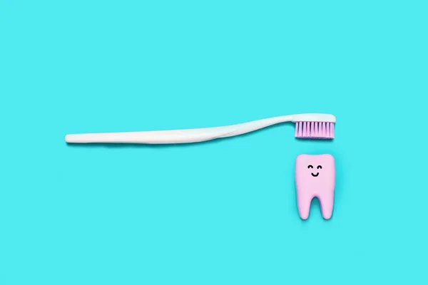 Toothbrush and big smiling tooth on blue background. Teeth care minimalism concept.