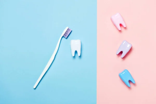 Toothbrush and big tooth on blue and pink background. Teeth care minimalism concept.