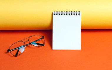 Kırmızı ve sarı arka planda gözlüklü not defteri. İş veya çalışma konsepti. Üst görünüm, düz yatıyordu. Metniniz için copyspace.