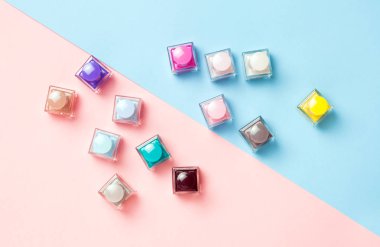 Pembe ve mavi arka planda birçok renkli ojeler. Düz yatıyordu. Üst te. Moda kozmetik seti.