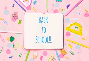 Çeşitli Okul aksesuarları ile renkli pembe arka plan bir gökkuşağı şeklinde ortaya koyulur. Boş defter. Düz yatıyordu üst görünüm. Çalışma düzenleme, istek listesi veya planları yapma. Okul metnine geri dön.