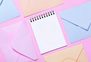Pembe masa üstü görünümünde renkli zarflar ve not defteri çerçeve. Mockup iş posta, bloglama ve ofis yazışmaları, motivasyon resmi için. Düz yatıyordu.