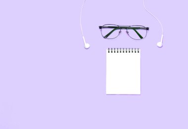 Gözlük ve mor masa üzerinde çeşitli Okul veya ofis aksesuarları ile Not Defteri. İş veya çalışma konsepti. Üst görünüm, düz yatıyordu. Metniniz için copyspace.