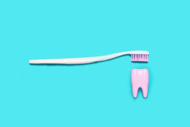 Diş fırçası ve mavi ve pembe arka plan üzerinde büyük diş. Diş Bakımı minimalizm kavramı.