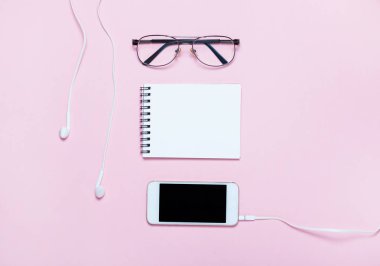 Pembe backgriund üzerinde gözlük ve kulaklık ile Dizüstü veya not defteri. Yaratıcı minimalizm şans kavramı. Üst görünüm, düz yatıyordu.
