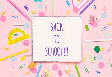 Çeşitli Okul aksesuarları ile renkli pembe arka plan bir gökkuşağı şeklinde ortaya koyulur. Boş defter. Düz yatıyordu üst görünüm. Çalışma düzenleme, istek listesi veya planları yapma. Okul metnine geri dön.