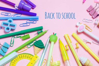 Çeşitli Okul aksesuarları ile renkli pembe arka plan bir gökkuşağı şeklinde ortaya koyulur. Boş defter. Düz yatıyordu üst görünüm. Çalışma düzenleme, istek listesi veya planları yapma. Okul metnine geri dön.