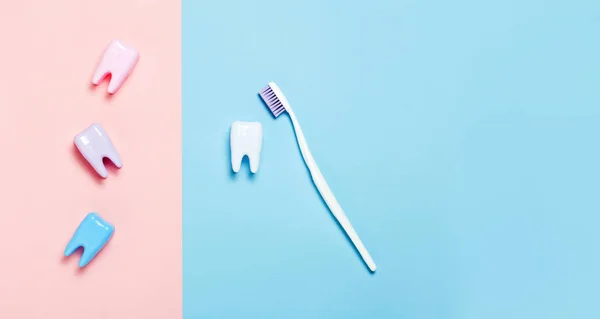 Toothbrush and big tooth on blue and pink background. Teeth care minimalism concept.