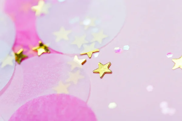 Pink confetti and stars and sparkles on pink background. Top view, flat lay. Copyspace for text. Bright and festive holiday background. For Christmas, New year, Mother\'s day.