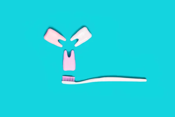 Toothbrush and big tooth on blue and pink background. Teeth care minimalism concept.