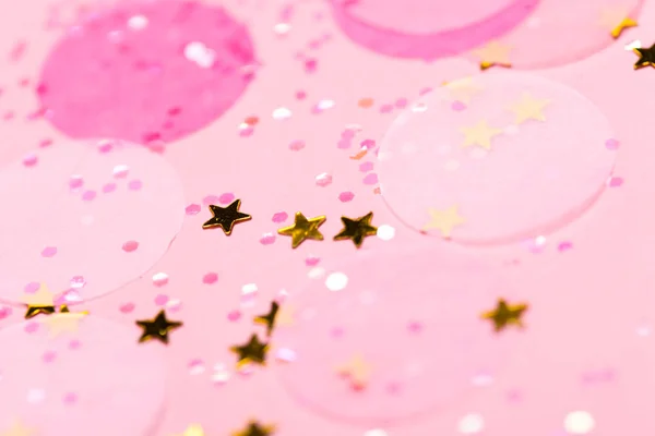 Pink confetti and stars and sparkles on pink background. Top view, flat lay. Copyspace for text. Bright and festive holiday background. For Christmas, New year, Mother\'s day.