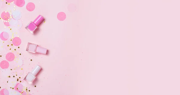 Pastel pembe tırnak cilaları ve konfeti, yıldız ve parıldıyor. Parlak ve festival arka plan. Manikür kavramı. Üstten görünüm, düz yatıyordu. metniniz için boşaltmak.