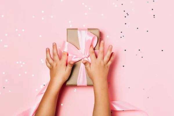 Dziecko ręce, trzymając piękne pudełko na różowym tle — Zdjęcie stockowe