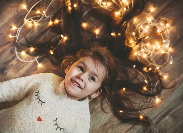 Sevimli küçük kız flor saçında parlak Noel çelenk ile döşeme.