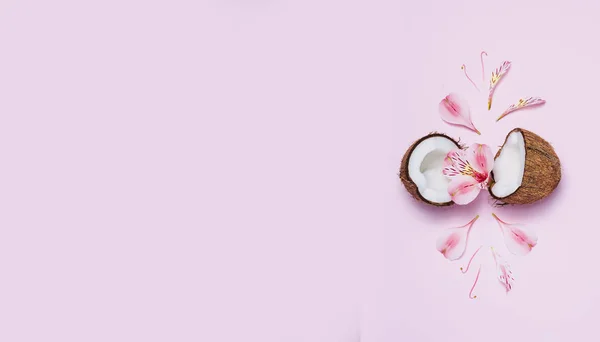 Coco roto con flores tropicales sobre fondo rosa . —  Fotos de Stock