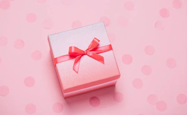 Różowe pudełko na różowe tło konfetti. — Zdjęcie stockowe