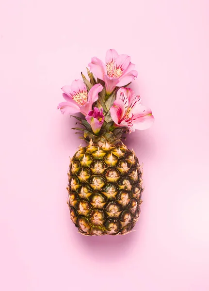 Ananas con fiori esotici su sfondo rosa . — Foto Stock