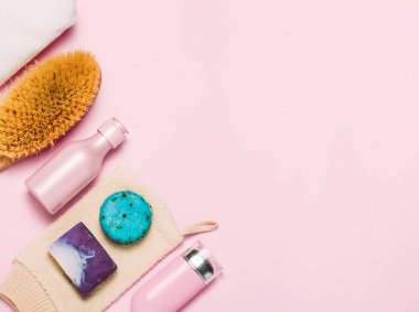 Spa kozmetik arka plan. Şişeler, vücut fırçası ve pembe arka plan üzerinde tropik yaprakları.