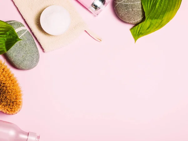 Fondo cosmético Spa. Botellas, cepillo corporal y hojas tropicales sobre fondo rosa . — Foto de Stock